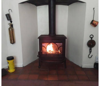 Jotul F100 multi-fuel stove in matt black -  with tracery door installed by our fitters in the Surrey Hills near Cranleigh.